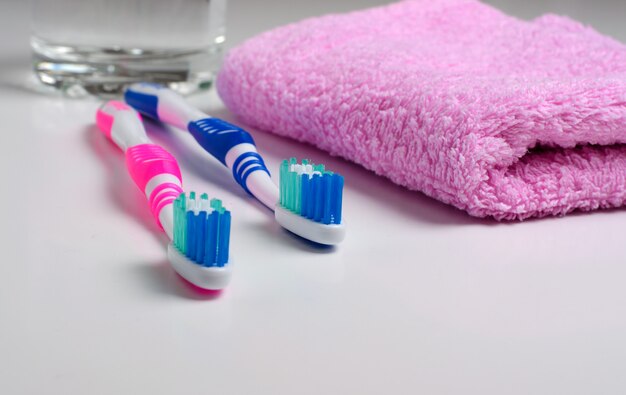 Two pink toothbrushes and pink towel