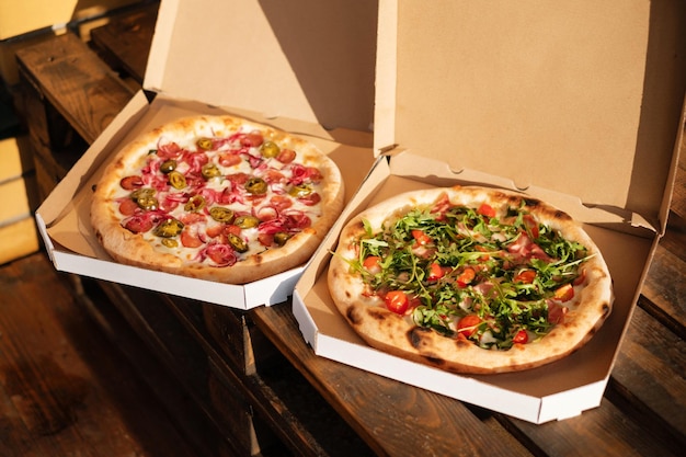 Two pizzas in cardboard boxes on a wooden background Eating outdoors