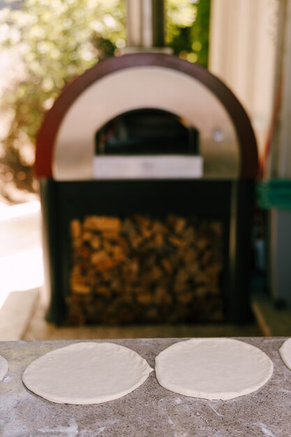 Foto due pizze da pasta cruda sullo sfondo del forno per pizza