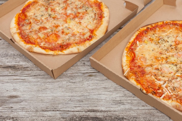 Two pizzas at paper boxes top view of fresh baked pizza with\
meat and vegetables on table delivery