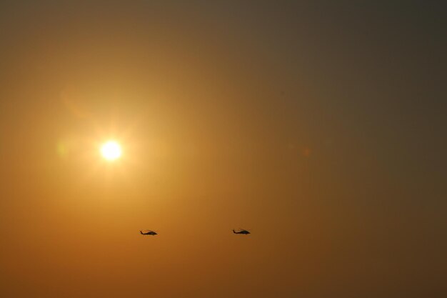 写真 2機の飛行機が太陽の後ろで空を飛んでいる