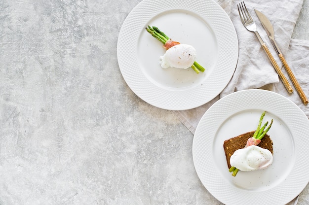Two plates with a poached egg on roasted asparagus wrapped in bacon. 