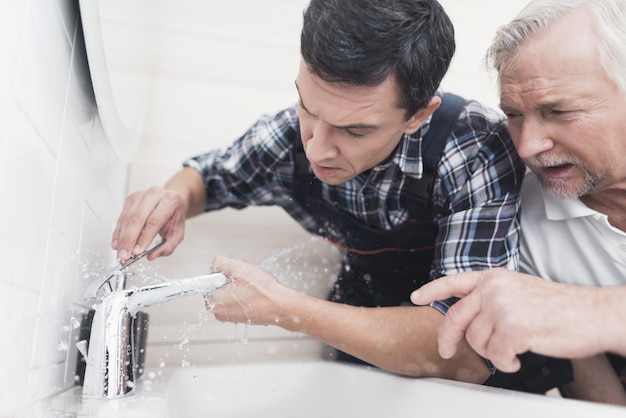 Two Plumbers Are Repairing Faucet In Bathroom.