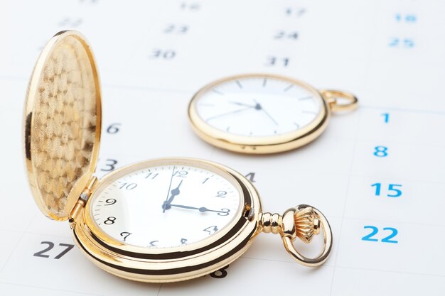 Two pocket watch against the wall of the calendar. Close-up.