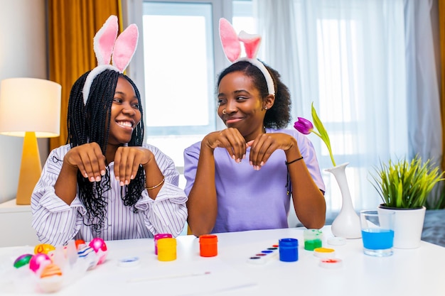 Two polyethnic pretty woman having fun and preparing to easter together