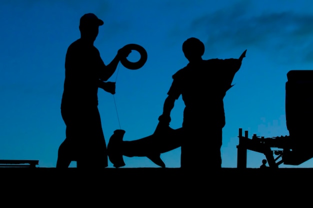 Two polynesian fisherman from Tonga before sunnrise in a silhouette with an hammerhead shark