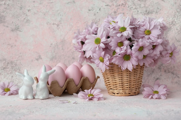 Foto due coniglietti in porcellana rosa uova un mazzo di fiori