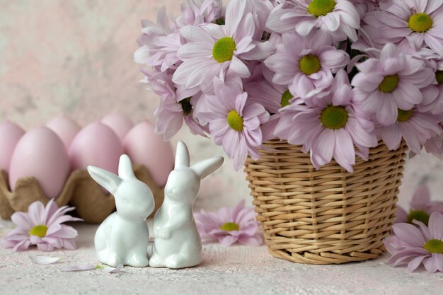 Foto due coniglietti in porcellana rosa uova un mazzo di fiori
