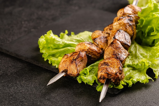 Two portions of shish kebab on a stone plate with salad.