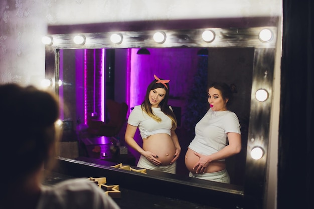 Two pregnant friends are waiting for their children showing belly