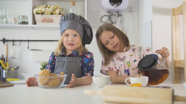 Two preschool girls bakers drinks tea close up