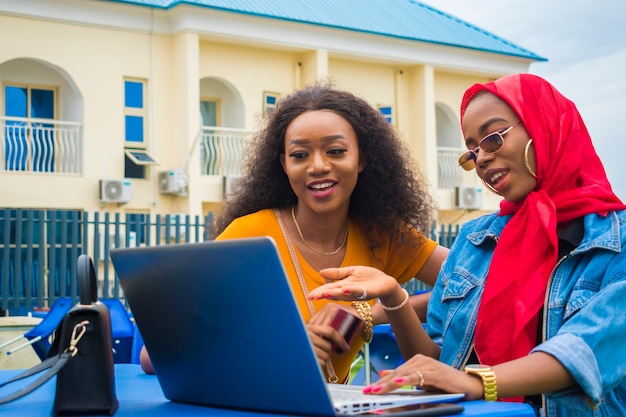 Two pretty african ladies using their credit card and laptop to shop online.