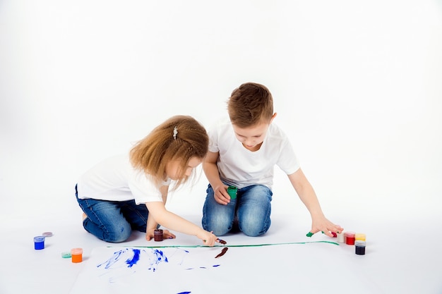 Two pretty child friends boy and girl are drawing pictures by paints