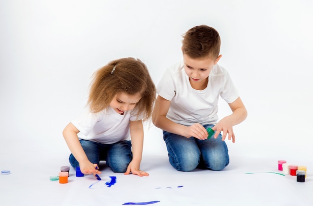 Two pretty child friends boy and girl are drawing pictures by paints