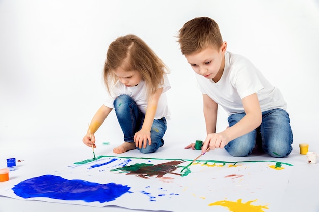 Two pretty child friends boy and girl are drawing pictures by paints