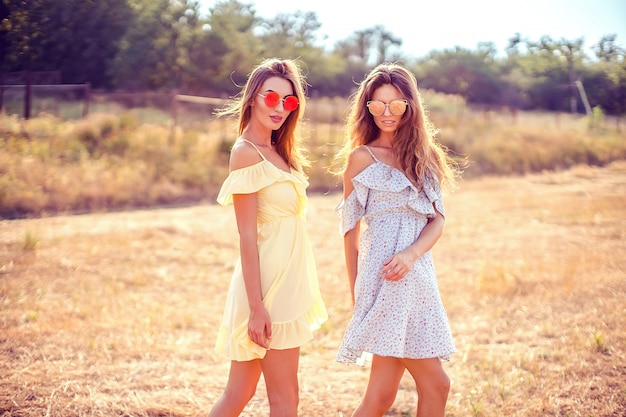 Two pretty girlfriends in summer dresses