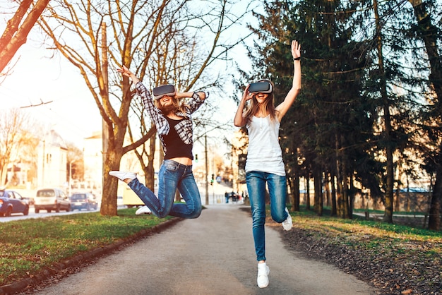 Photo two pretty girls enjoy virtual reality glasses outdoor