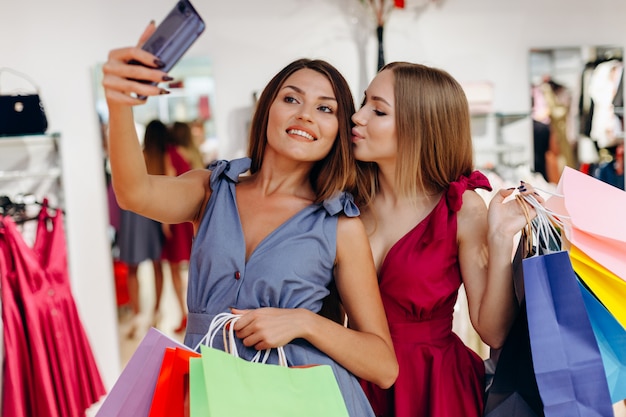 Two pretty girls take selfies after shopping at the store