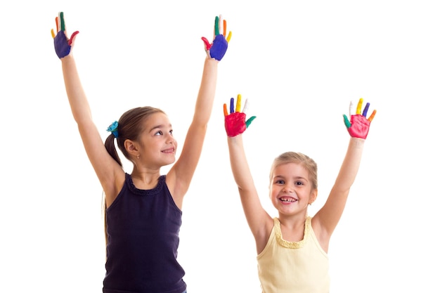 Two pretty little girls in black and yellow shirts with ponytails and colored hands in studio