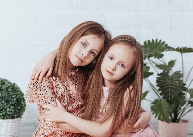 Две симпатичные маленькие девочки-сестры счастливо обнимаются и смеются