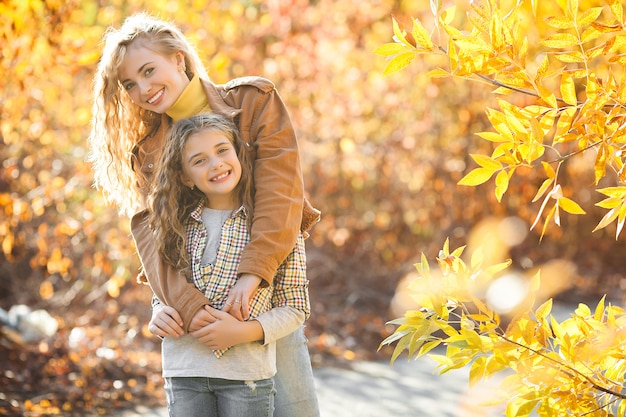 Two pretty sisters walking together in autumn. Cheerful girls. Fall concept.