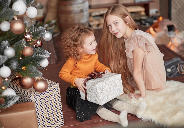 Two pretty sisters with presents sitting on the floor on christmas eve