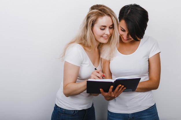 Two pretty women making note in notebook. Happy emotion. 