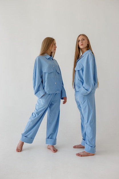 two pretty young twin sisters with long blond hair posing