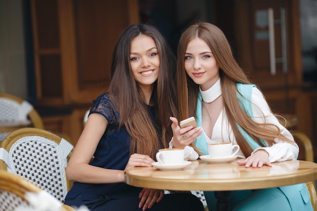 two pretty young women in cafe with coffee and phone