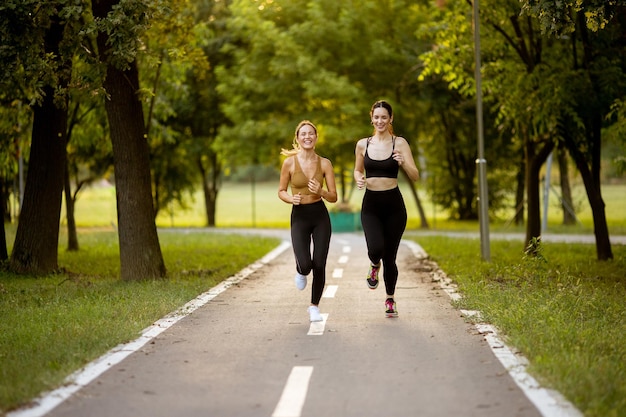 Two pretty young women running on the lane in the park