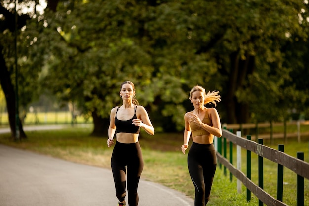 Photo two pretty young women running in the park