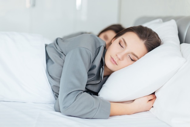 Two pretty young women sleeping in bedroom together