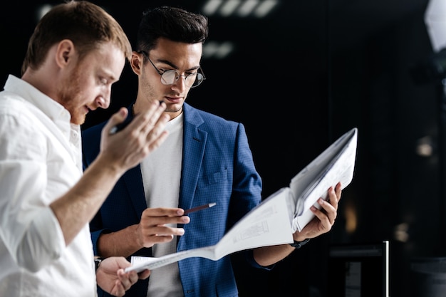 Two professional architects discuss sheet with drawing in the office .