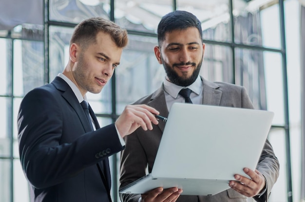 Two professional businessmen discussing and using desktop computer in office