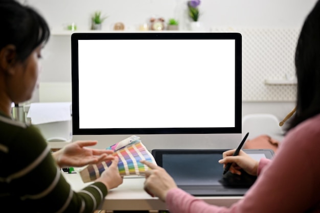 Two professional graphic designers discussing working together in the studio computer mockup