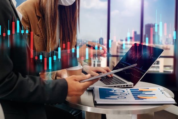 Two professional traides on technical price graph and indicator, red and green candlestick chart and stock trading computer at office