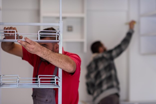 Foto due lavoratori professionisti che installano un nuovo ed elegante mobile da cucina moderno