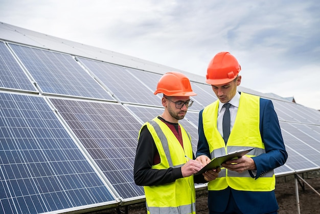 Due professionisti dell'abbigliamento da lavoro discutono dei pannelli solari e del loro impatto il concetto di elettricità verde e il suo impatto