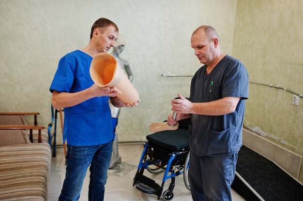 Two prosthetist man workers with prosthetic leg working in laboratory.