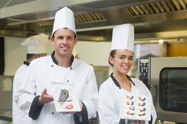 Two proud chefs presenting dessert plates