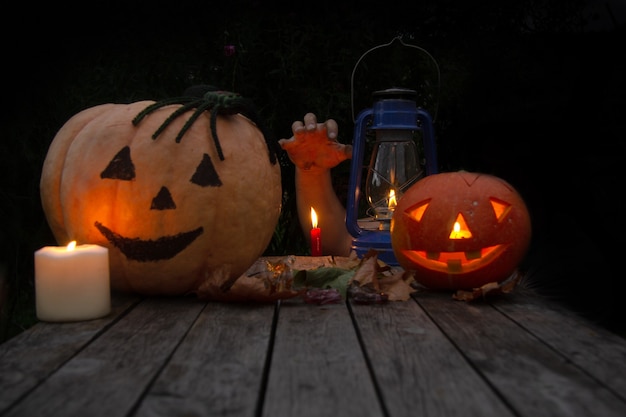 Photo two pumpkins with eyes stand on a wooden table next to them candles a kerasin lamp halloween