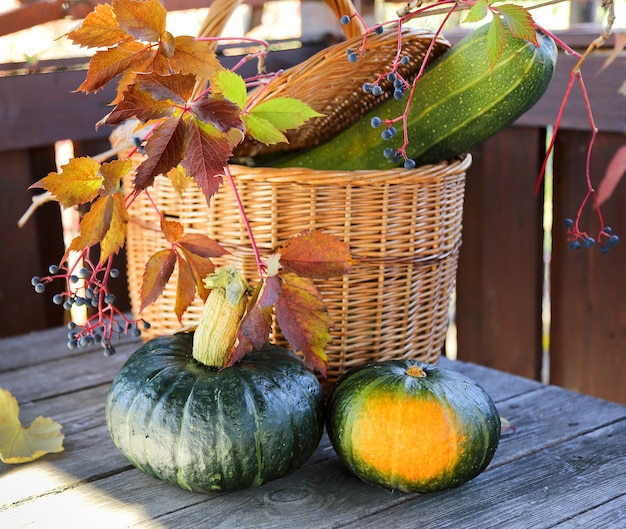 Two pumpkins on a wooden table on a background of a wicker basket
