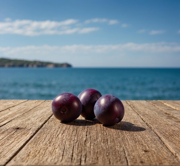 two purple plums on a wooden table with the ocean in the background