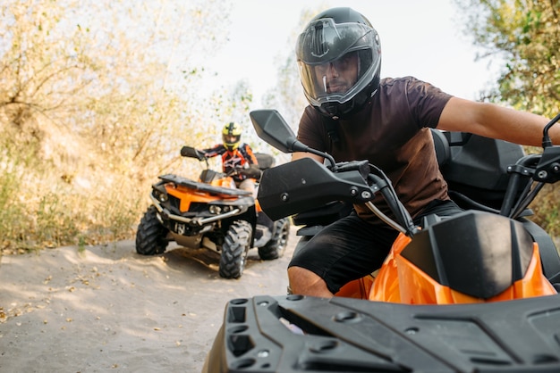 Two quad bike riders travels in forest, front view