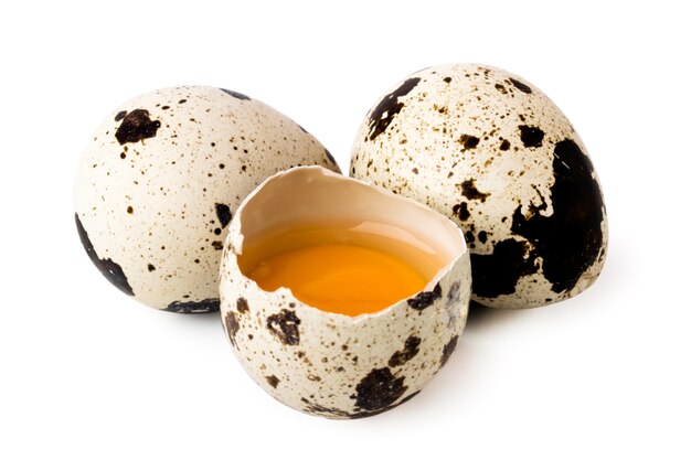 Two quail eggs and broken on white