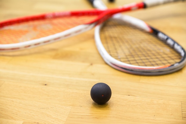 Two rackets and squash balls lie on the parquet floor Horizontal photo