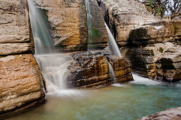 Two rapid waterfall streams flowing down the rock in Martvili canyon on autumn day