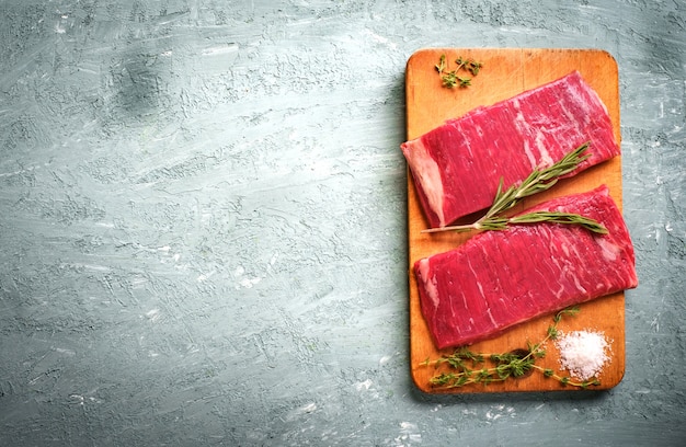 Two raw flank steak on wooden board