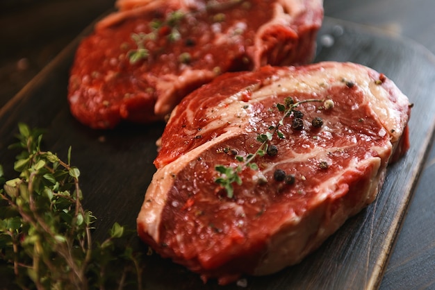 Two raw marbled beef steaks in olive oil and spices ready for frying.