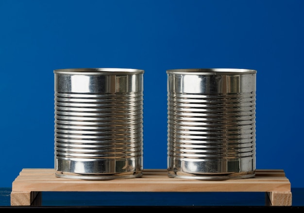 Two recycled cans on wooden boards with blue background